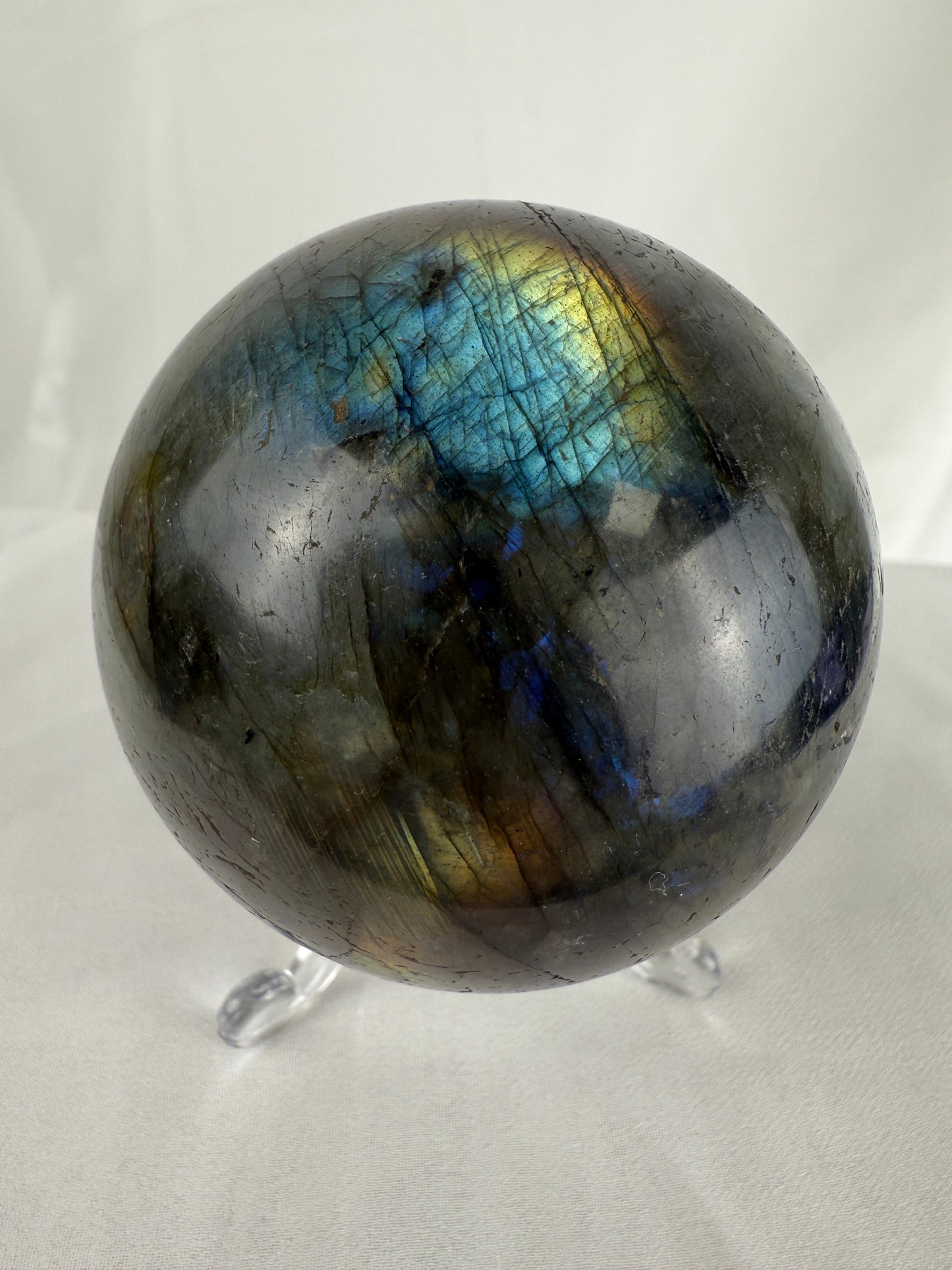 Labradorite crystal sphere on a stand with a white background