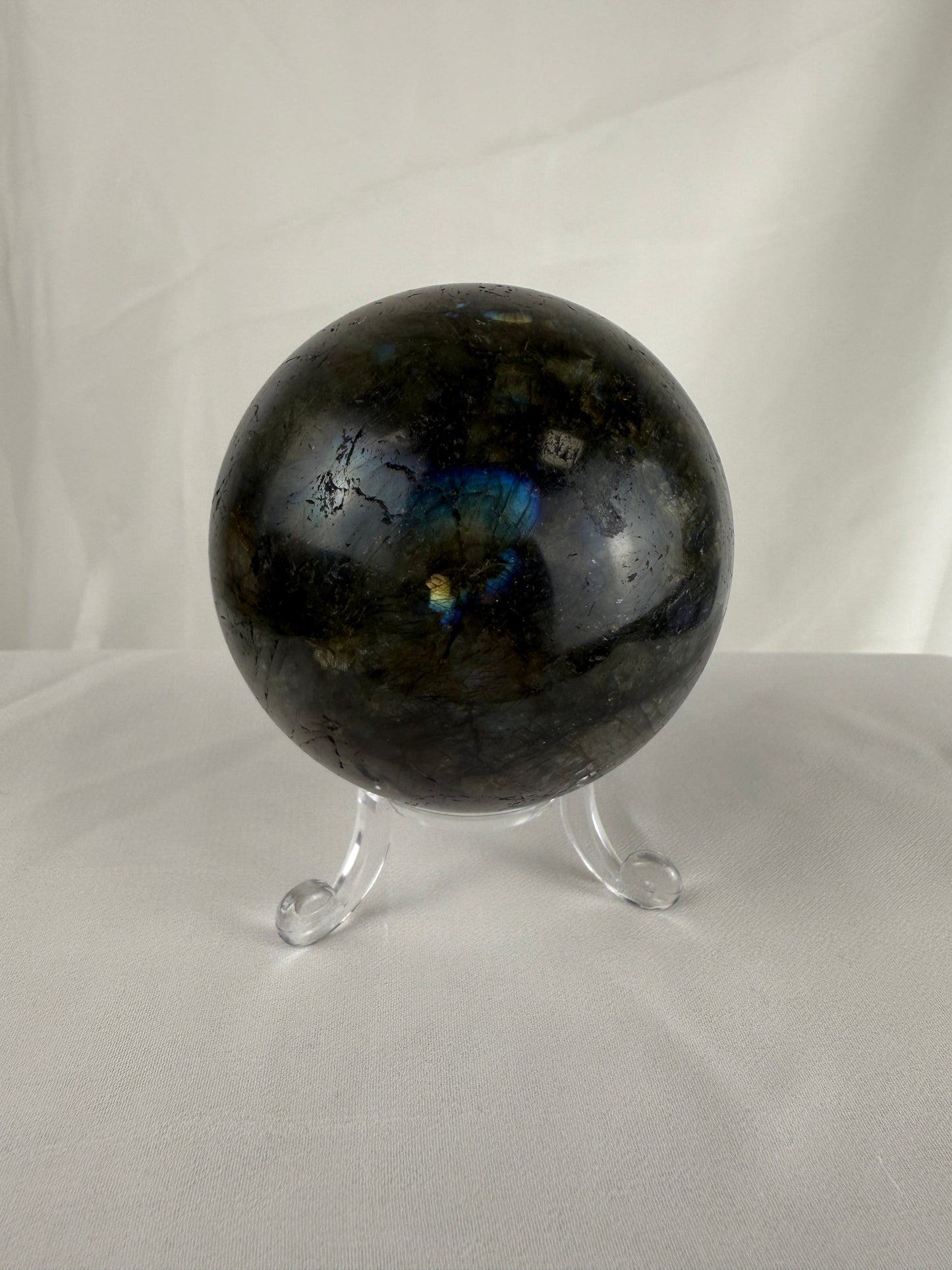 Labradorite crystal sphere on a stand against a white background