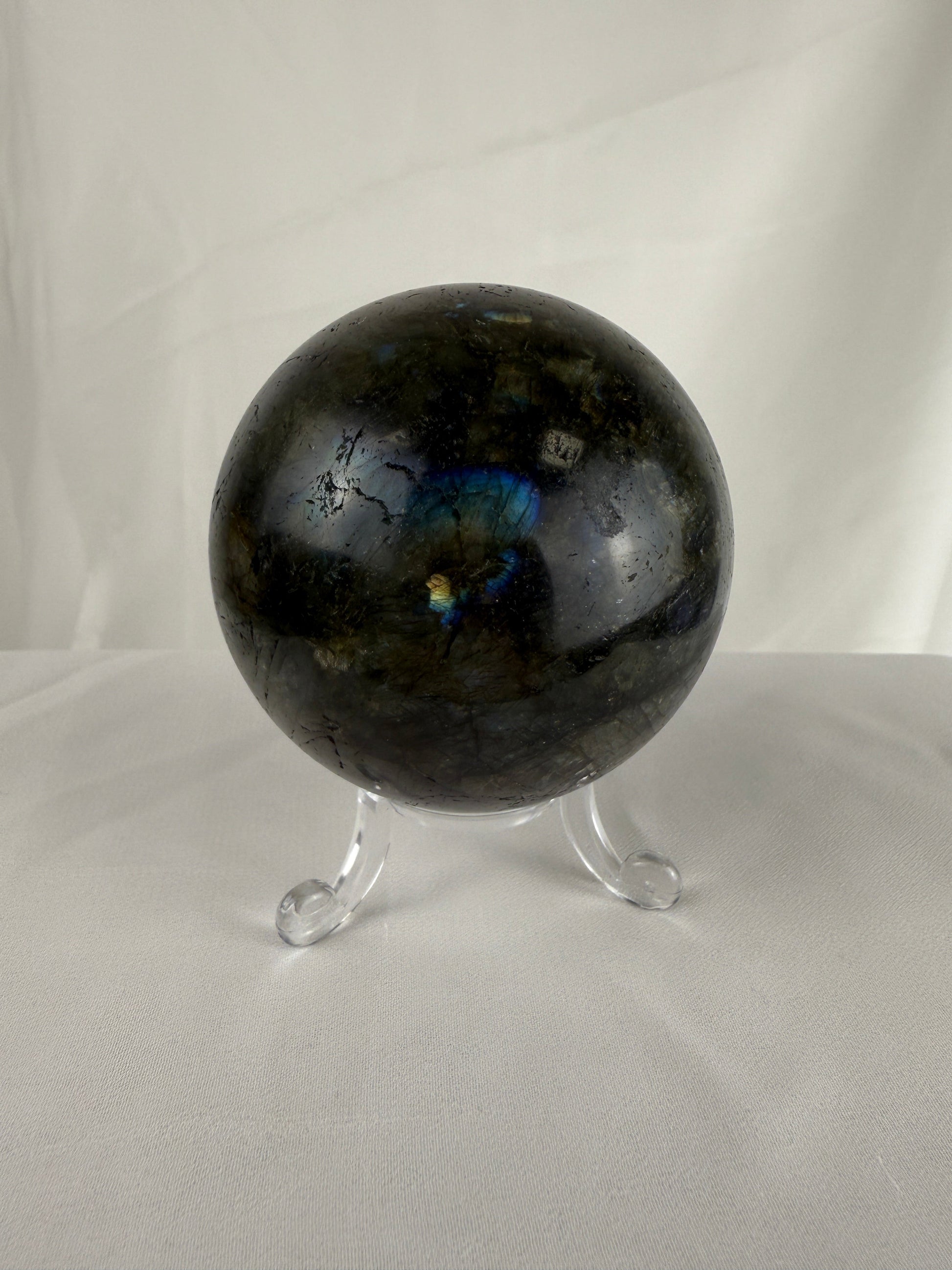 Labradorite crystal sphere on a stand against a white background