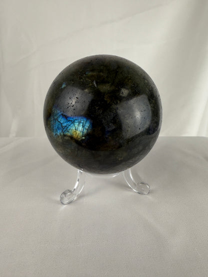 Black labradorite sphere on a stand against a white background